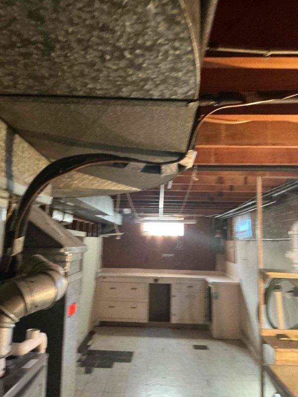 Responded to service call for reported water leak from furnace with suspected condensation line issue. Upon arrival, performed thorough inspection of HVAC system including furnace unit, blower assembly, and PVC condensate drain piping. Investigated condensation line connections and drainage system for potential leaks or blockages. Measured and assessed furnace cabinet clearances and component spacing to identify source of moisture. Examined blower motor assembly and surrounding areas for water damage or accumulation. Inspected ductwork, ventilation components, and basement installation for proper drainage and condensate removal. Documented system conditions with detailed photographs of furnace interior components and mechanical room layout for service records.