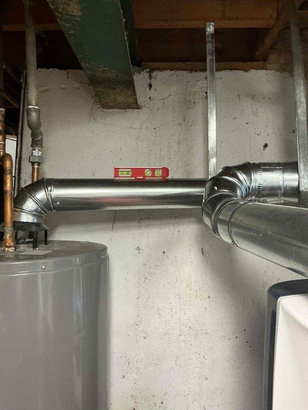 Corrected improper venting configuration by pitching the flue pipes for both the water heater and furnace to ensure proper condensate drainage and safe exhaust operation. Removed the existing 7-inch tee fitting and replaced it with a Y-fitting, reducing connections down to 4-inch diameter for both appliance vent pipes to meet code requirements and manufacturer specifications. Verified proper pitch and secure installation of all ductwork connections to optimize system performance and safety.