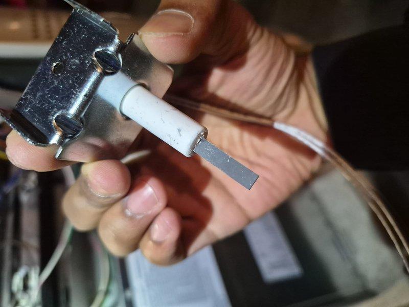 Replaced faulty hot surface ignitor (HSI) on furnace system. Removed defective ceramic ignitor assembly with metal mounting brackets and installed new component. Verified proper ignition sequence and confirmed burner assembly firing with even blue flame pattern across all burner tubes upon system startup.