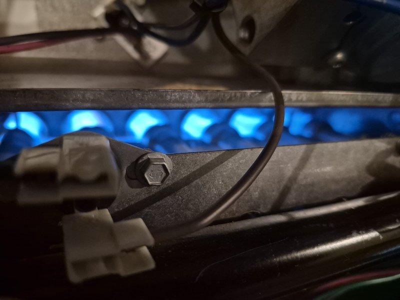 Replaced faulty hot surface ignitor (HSI) on furnace system. Removed defective ceramic ignitor assembly with metal mounting brackets and installed new component. Verified proper ignition sequence and confirmed burner assembly firing with even blue flame pattern across all burner tubes upon system startup.