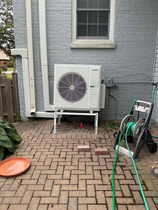 Responded to service call for two-unit HVAC system with reported water leak on one unit and cooling failure with intermittent shutdown on the second unit. Inspected exterior-mounted Bosch heat pump unit positioned on metal bracket stand in side yard area. Evaluated condensate drainage system, refrigerant lines, and electrical connections on the affected unit. Assessed operational status of both systems, documented equipment information, and photographed installation for service records.