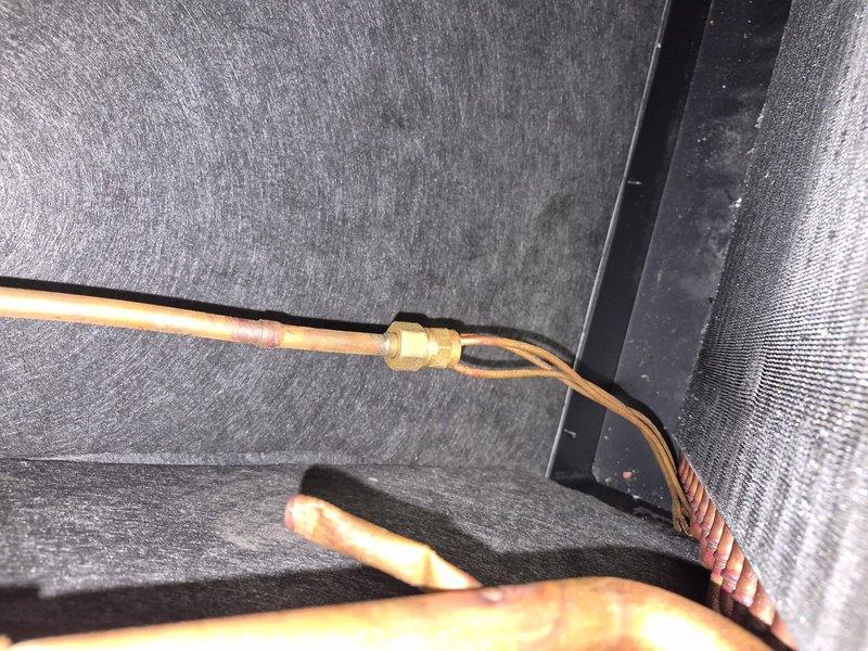 Responded to no cooling complaint and performed diagnostic evaluation of residential air conditioning system. Inspected thermostat wiring connections at terminal block, verified proper wire placement for Y, G, C, R, and O/B terminals, and confirmed correct system configuration. Examined refrigerant line set connections at indoor unit, checking brass flare fittings and copper tubing routing for proper installation and potential refrigerant leaks.