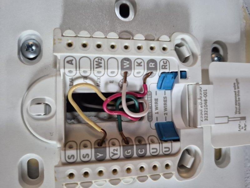 Responded to no cooling complaint and performed diagnostic evaluation of residential air conditioning system. Inspected thermostat wiring connections at terminal block, verified proper wire placement for Y, G, C, R, and O/B terminals, and confirmed correct system configuration. Examined refrigerant line set connections at indoor unit, checking brass flare fittings and copper tubing routing for proper installation and potential refrigerant leaks.