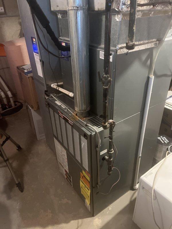 Completed comprehensive assessment of existing HVAC system located in residential basement, including aging furnace with vertical flue pipe and external AC condenser unit positioned at building exterior. Documented current equipment conditions, measured installation space requirements, photographed existing ductwork connections and utility room layout, and provided detailed replacement estimate for new air conditioning system and furnace due to equipment age and obsolescence.