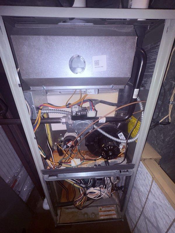 Completed comprehensive Comfort Plan clean and check service on HVAC system, performing both spring air conditioning and fall furnace maintenance procedures. Inspected and serviced blower motor assembly, noting visible wear and oxidation on copper components; verified electrical connections throughout system including compressor unit, control wiring, and terminal blocks. Documented internal cabinet conditions with all mechanical and electrical components operating within normal parameters upon completion of preventive maintenance protocol.