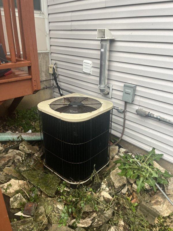 Conducted on-site evaluation for complete HVAC system replacement at residential property. Assessed existing outdoor condenser unit positioned on grade-level stone base against exterior wall and evaluated basement furnace installation within existing utility space. Performed measurements of available clearances and documented current equipment configuration, ductwork connections, and utility routing including gas lines, electrical service, and condensate drainage to prepare comprehensive replacement quote for new air conditioning and heating system.