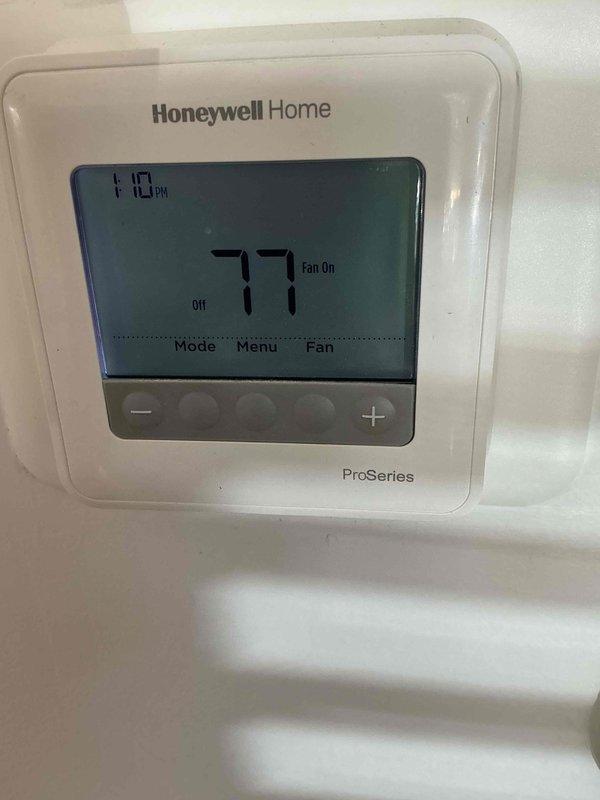 Responded to a no-cooling complaint and inspected the indoor Rheem gas furnace/air handler in the utility room, including the flue connection and cabinet condition, noting rust and discoloration at the base of the unit. Verified thermostat operation at the Honeywell Home ProSeries control, which was set to "Off" with the fan in the "On" position at a 77° indoor reading. Documented equipment information and system condition for service records.