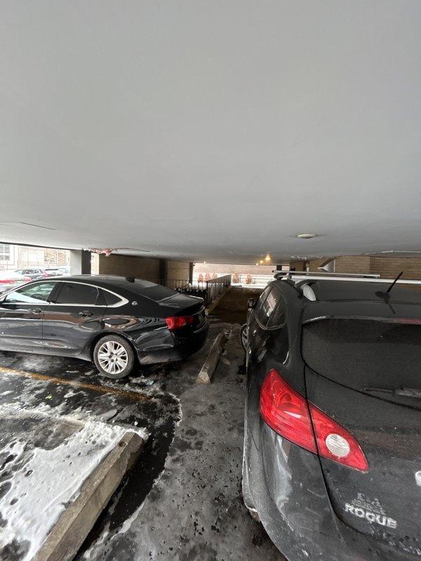 Responded to service call regarding outdoor electrical fixtures. Upon arrival, inspected indoor parking garage and covered parking area, noting damaged ceiling with exposed insulation above a parked vehicle. Contacted customer (Mike) by phone for specific issues as he was not on-site.