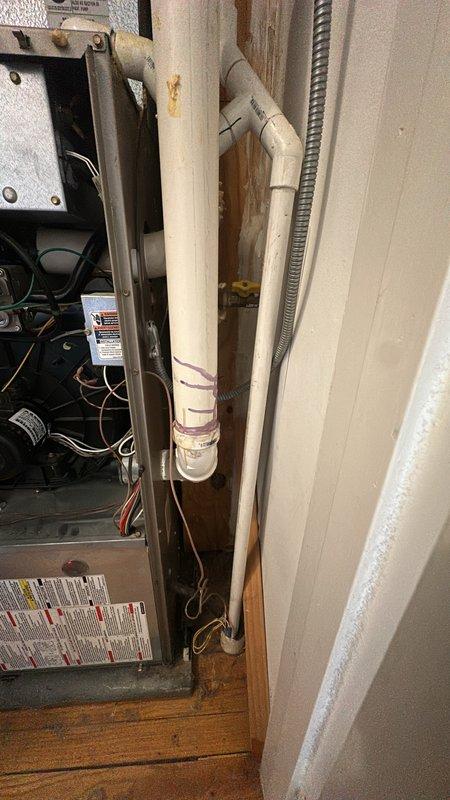 Performed diagnostic inspection on heating unit after tenant reported burnt smell. Examination of the furnace revealed exposed internal components including circuit board and wiring. Found water staining and deterioration around pipe installation area, which may be contributing to electrical issues causing the burnt odor. Recommended replacement of damaged components and sealing of water-compromised areas to prevent further damage.