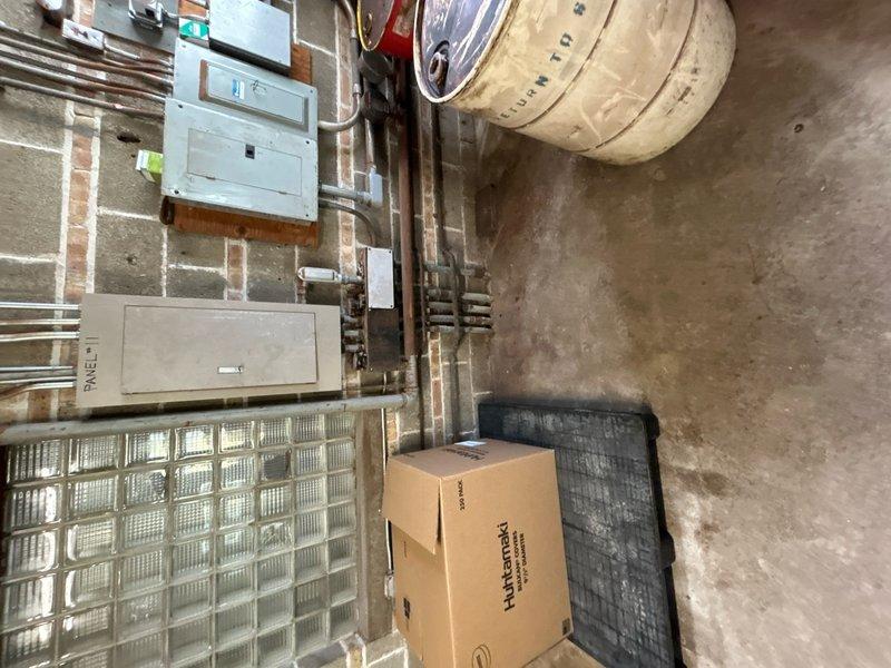 Conducted site assessment for quote amendment to incorporate exterior electrical outlets. Documented existing conditions including exterior service area with accessible wall space near waste receptacle location and basement utility room showing current electrical panel and infrastructure. Photographed proposed installation areas to facilitate accurate pricing for additional exterior outlet installation work.