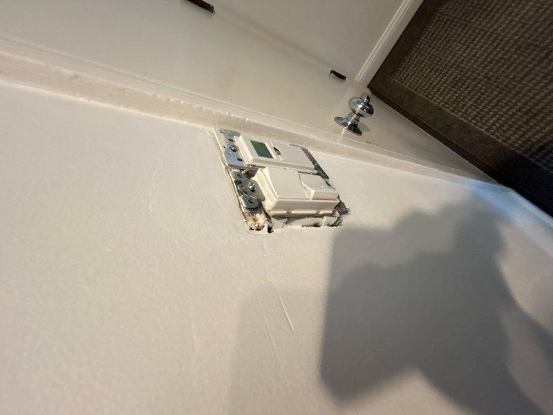 Performed comprehensive assessment of existing electrical panel for replacement quote. Documented current panel configuration showing multiple circuit breakers with several red-handled breakers indicating potential Federal Pacific or similar older equipment requiring replacement. Photographed panel interior revealing circuit layout, existing labeling system with yellow notes, and overall condition of breaker arrangement. Also documented related electrical components including wall-mounted thermostat or control device to ensure compatibility considerations for new panel installation.