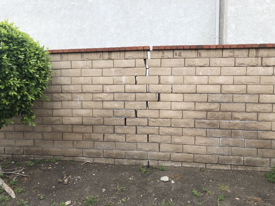 Wall with significant damage caused more than likely by tree roots pushing up.