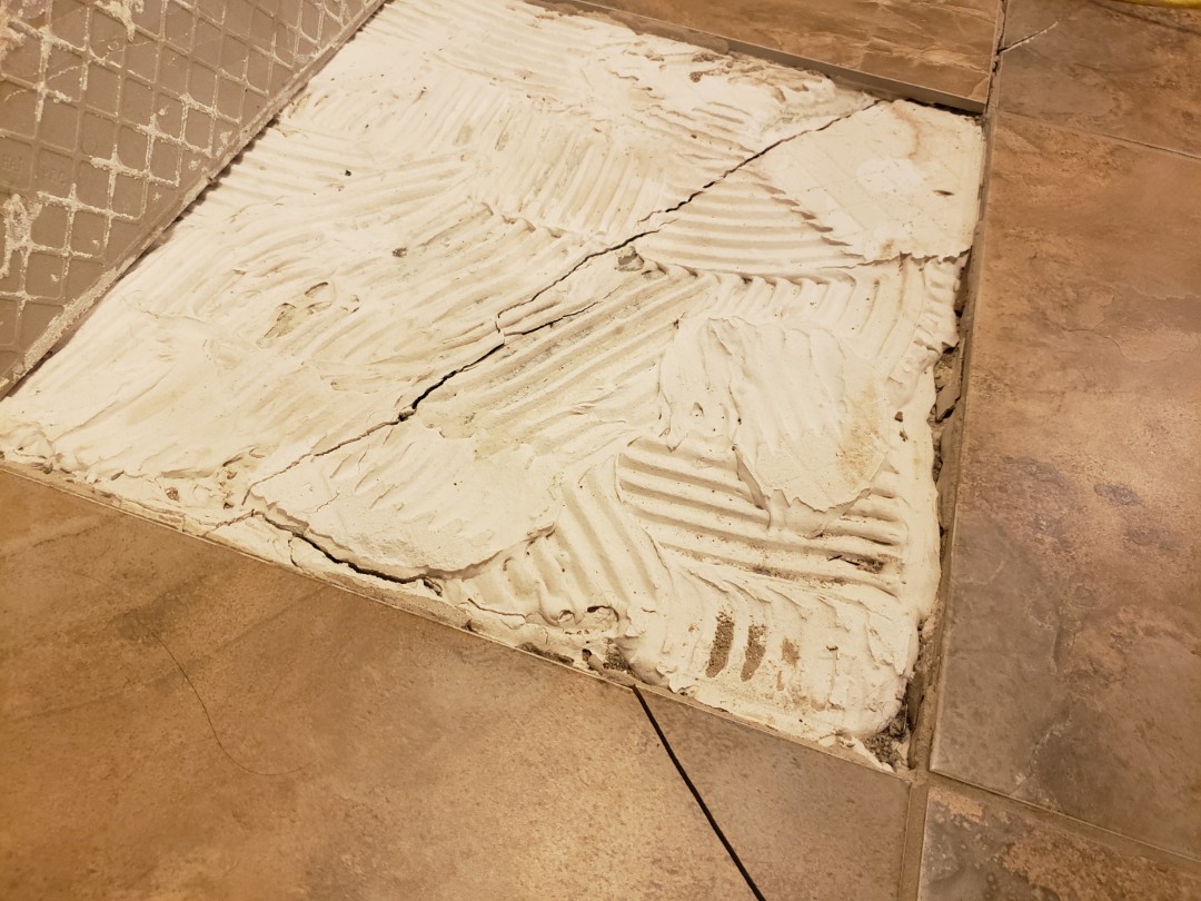 Settlement by more than -1.5" resulting in a cracked slab and lifting tiles.