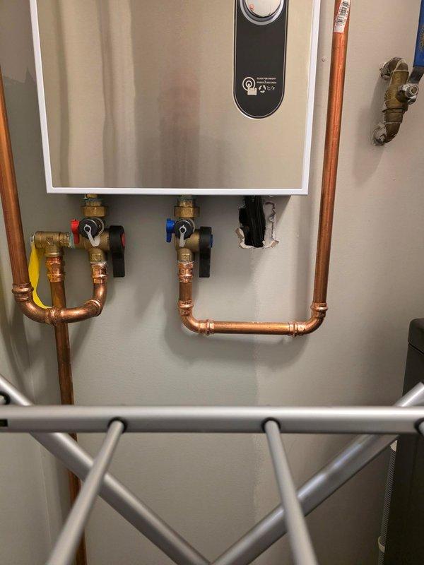Responded to call back regarding improper installation of tankless water heater. Identified exposed electrical wires at bottom knockout of unit where installation crew had created rough hole through drywall without proper finishing or conduit protection. Properly secured electrical connections and repaired wall penetration to meet code requirements and ensure safe operation.