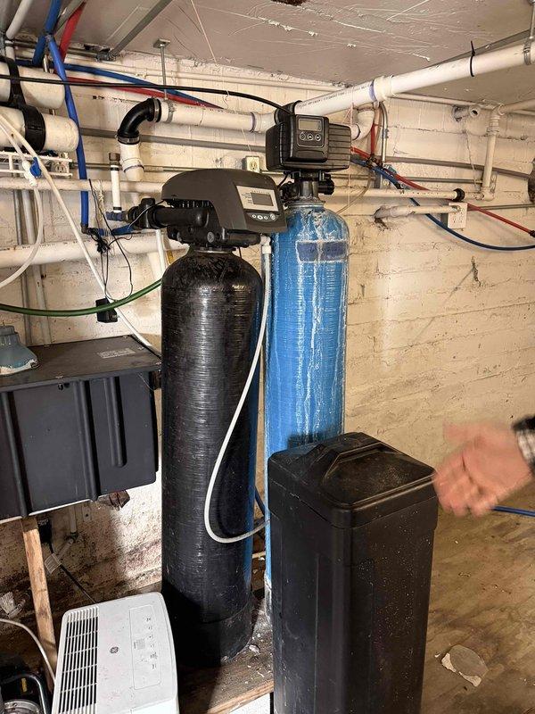 Conducted a comprehensive evaluation of an aging water softener system with dual tanks (black and blue) as requested by customer. Upon inspection, identified the system as functioning properly despite its age, with no immediate repairs needed. Verified proper operation of control panels, connections, and checked for any leaks in the surrounding plumbing infrastructure. Customer was advised on expected remaining lifespan and potential future maintenance requirements.