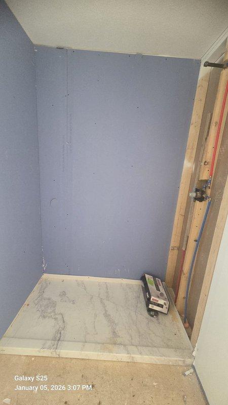 Completed rough-in installation of bathtub and shower unit with built-in shelving niches. Confirmed proper positioning of drain hardware and wall-mounted faucet/shower controls. Unit is now ready for final connections and fixture installation.