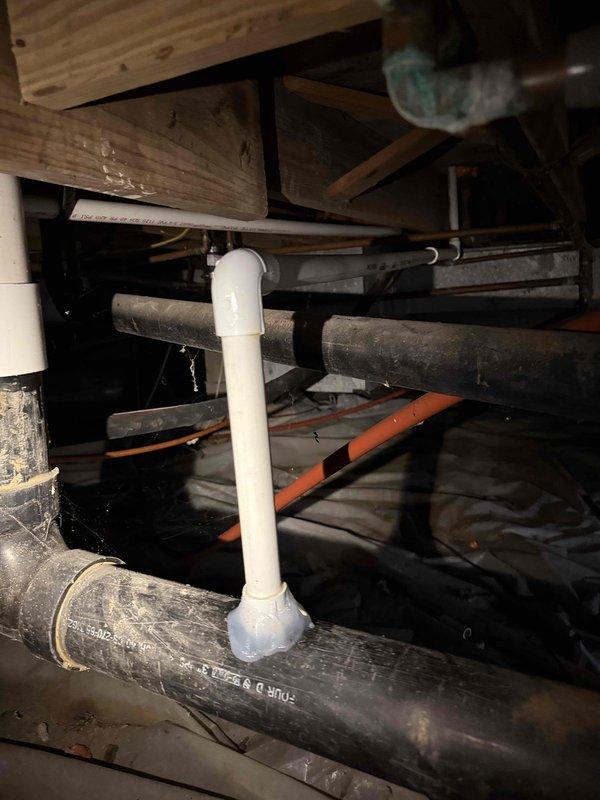 Inspected plumbing infrastructure in crawlspace to investigate gurgling sounds occurring during toilet flushes. Examined the connection between furnace drain pipe and sewer line, which was previously installed. Discovered the cause of the gurgling noise was related to the drain pipe configuration where the white PVC pipe connects to the black ABS drain pipes.