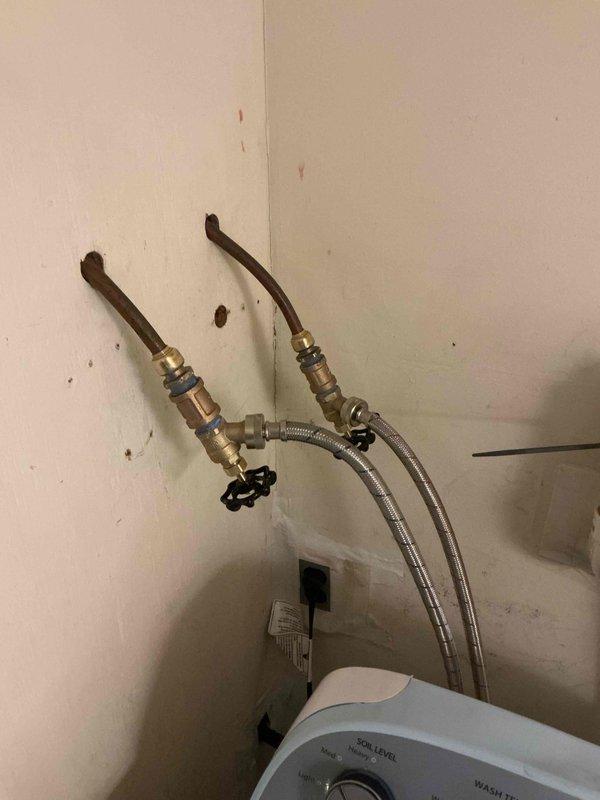 Responded to leak in washer connection valve. Upon inspection, found corroded copper pipe with failing valve assembly behind washing machine. Replaced damaged valve assembly and installed new braided stainless steel supply lines. Also leveled washing machine as requested by customer to prevent future stress on connections.
