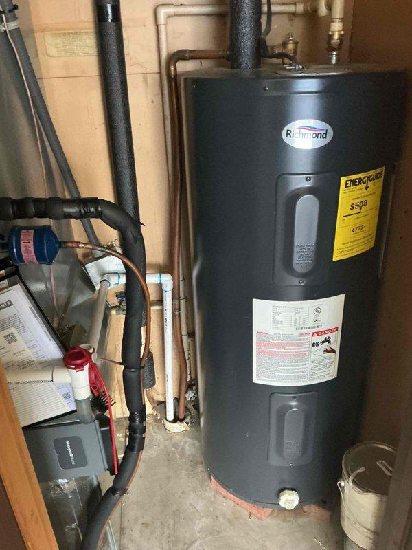 Responded to customer complaint of buzzing noise behind bathroom vanity. Upon inspection, identified water leak in supply lines with water turned off at source. Documented existing water heater installation for reference, noting proper connections of copper and PVC piping to Richmond unit.