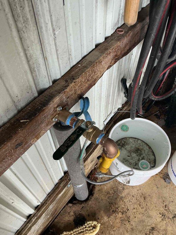 Responded to emergency call for burst water line in garage causing flooding. Customer had shut off main water valve in yard. Located and repaired damaged pipe section against corrugated metal wall, installed new valve assembly with proper fittings, and collected overflow water in buckets during repair process. Restored water service and verified proper operation with no leaks.