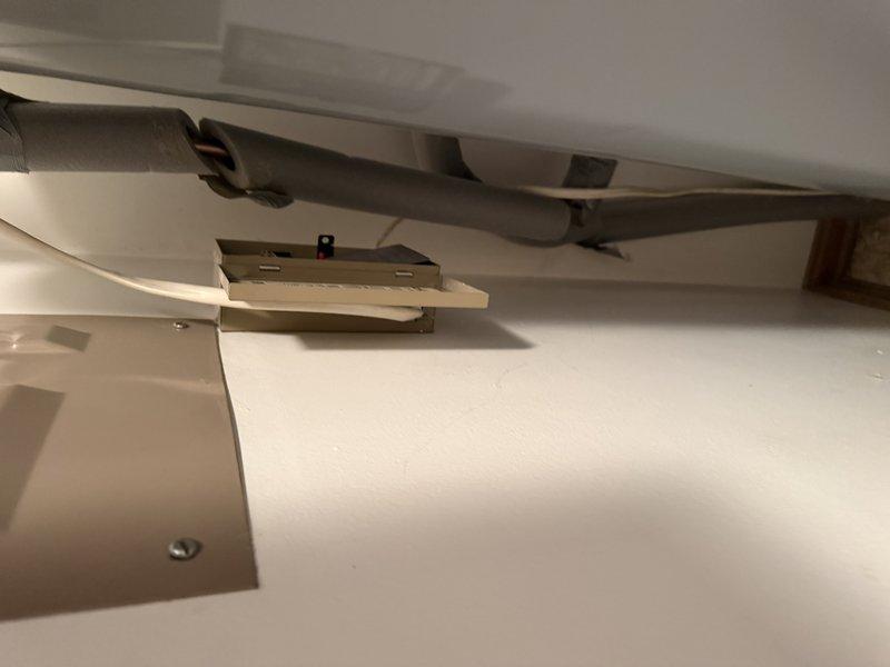 Responded to emergency service call for water heater leak reported by customer. Upon inspection, examined plumbing connections at water heater tank, focusing on hot and cold water line connections with their respective red and blue connector rings. Also inspected the electrical junction box and ventilation components. No active leaks were identified during inspection.