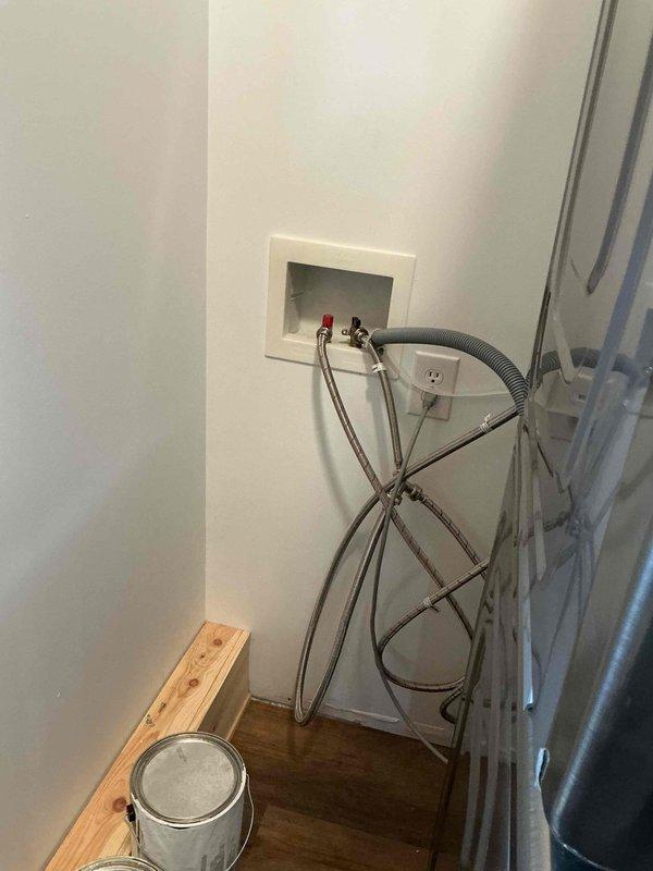 Completed winterization service on exposed water supply lines in utility area. Insulated braided metal hoses and connection points at recessed wall box containing red and black valves to prevent freezing during cold weather. Inspected surrounding plumbing components to ensure proper protection against winter temperatures.