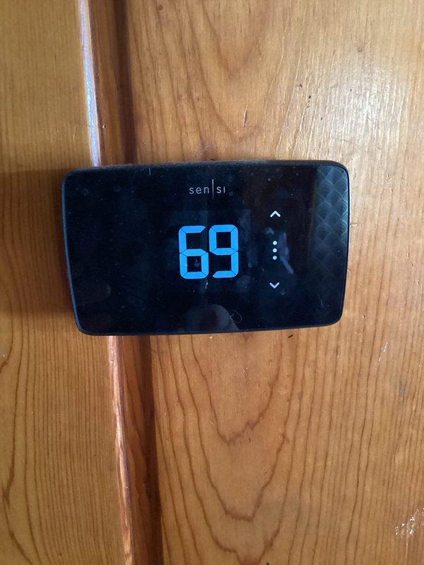 Responded to customer complaint of furnace cycling between hot and cold air. Inspected system including thermostat (Sensi model) reading 69°F and exterior Bryant heat pump unit which was heavily covered with snow. Cleared snow accumulation from outdoor unit to restore proper airflow and system operation.