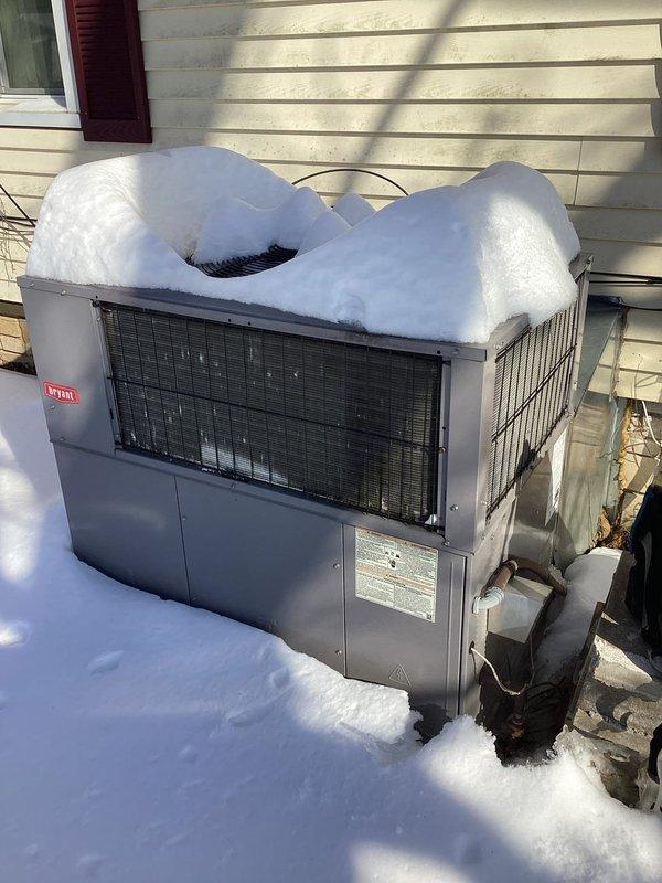 Responded to customer complaint of furnace cycling between hot and cold air. Inspected system including thermostat (Sensi model) reading 69°F and exterior Bryant heat pump unit which was heavily covered with snow. Cleared snow accumulation from outdoor unit to restore proper airflow and system operation.