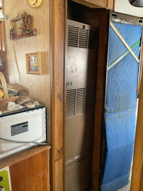 Performed on-site assessment of customer's 30+ year old heating system with failed gas valve. Unit is a wall-mounted furnace installed in a compact living space with wooden paneling. Inspection revealed significant age deterioration and ventilation issues. Recommended complete system replacement due to obsolete components and inefficiency. Customer indicated urgency for installation with preference for immediate scheduling.