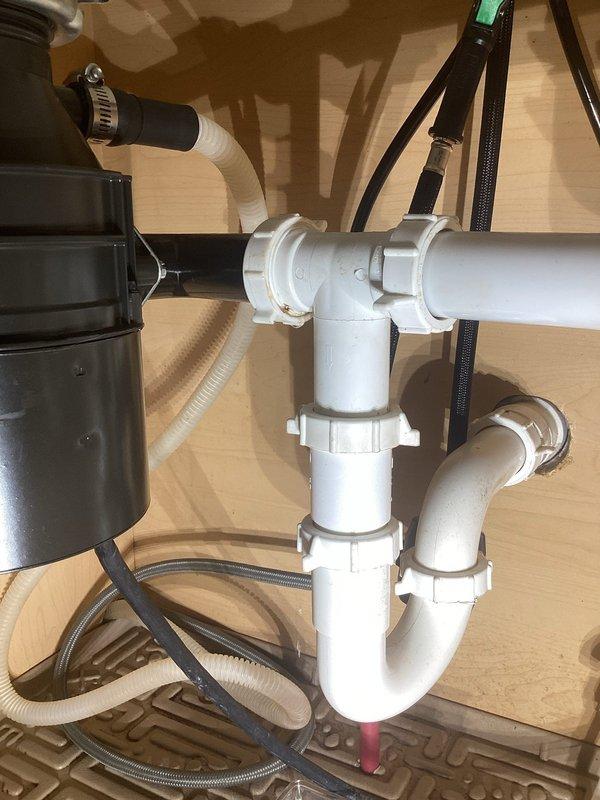 Responded to customer call regarding leak under kitchen sink. Diagnosed issue with faulty P-trap assembly. Removed existing white PVC drain components, replaced with new P-trap configuration, and verified proper connection to garbage disposal unit. System tested with no leaks observed after repair.