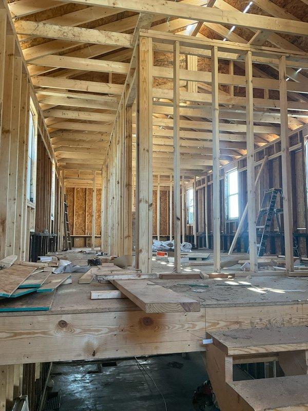 Completed site evaluation for new HVAC system installation in residential remodel currently in framing stage. Property features exposed wooden studs, unfinished plywood flooring, and high ceilings with exposed rafters. Coordinated with plumbing team for integrated mechanical systems planning.