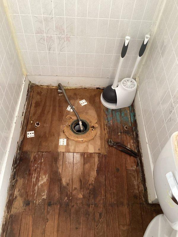 Responded to service call for water gurgling in utility room and backed up drains. Performed drain clearing procedure using mechanical snake/auger on bathroom floor drain. Observed significant water damage to wooden flooring around drain area, indicating prolonged drainage issues that were successfully addressed.
