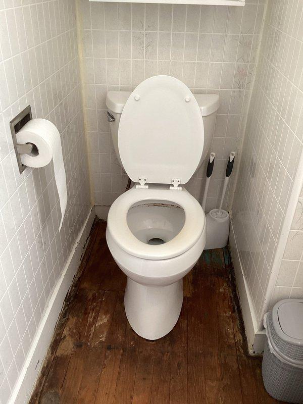 Responded to service call for water gurgling in utility room and backed up drains. Performed drain clearing procedure using mechanical snake/auger on bathroom floor drain. Observed significant water damage to wooden flooring around drain area, indicating prolonged drainage issues that were successfully addressed.