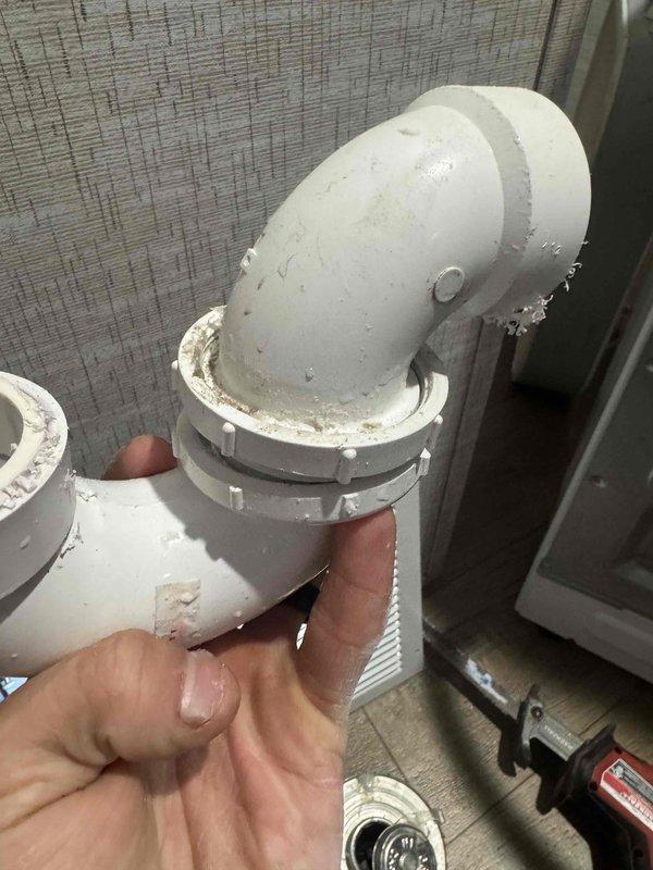 Responded to service call for washing machine drainage issue where water was discharging onto floor instead of through proper drain. Discovered clogged drain line caused by improper disposal of "flushable" wipes. Removed and inspected PVC elbow joint connection, cleared blockage using auger, and reinstalled plumbing components with proper sealing to restore normal drainage function.