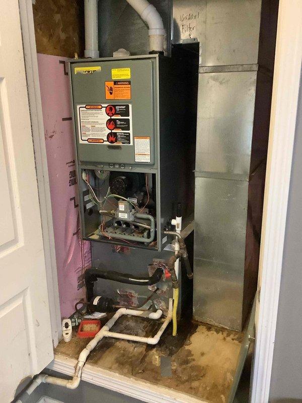 Performed diagnostic assessment on Ruud HVAC system, identifying moisture issues near the furnace base with visible staining on the floor. Inspected internal components including control boards, wiring, and heating elements, along with examining the condensate drain line which appears to be the source of the moisture problem. Noted outdoor condenser unit requires vegetation management around its perimeter for optimal airflow.