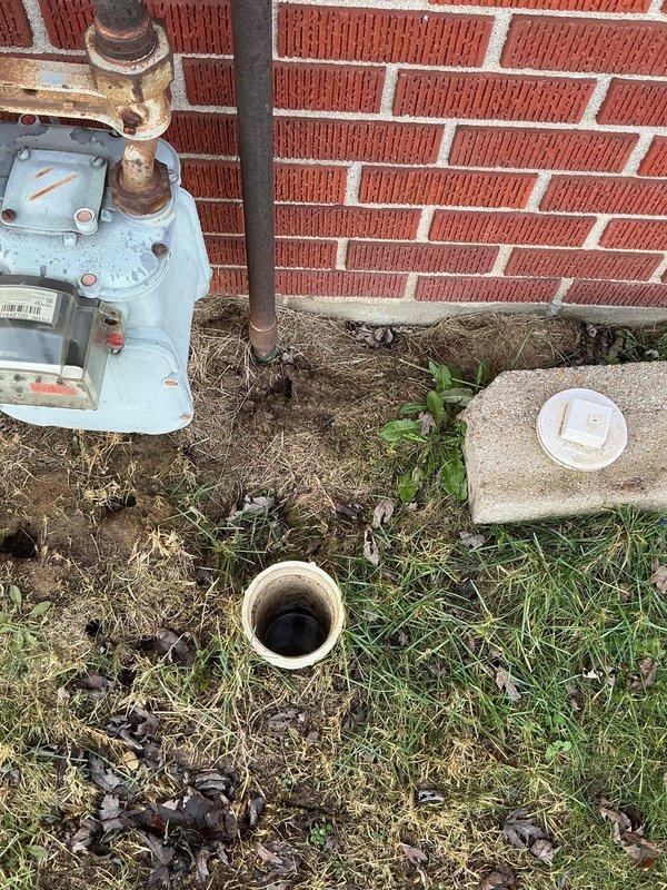 Responded to service call for clogged exterior drain pipe. Upon inspection, found significant staining and sediment buildup in the cylindrical PVC drainage pipe located in the yard area. Cleared blockage and debris from drain opening, restoring proper drainage function.