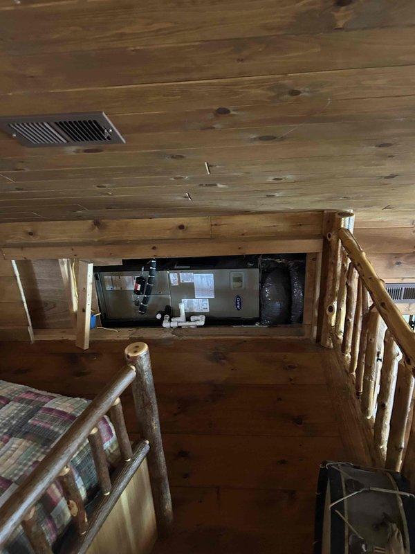 Successfully replaced evaporator coil in cabin-style residence with wood-paneled interior. Equipment was properly installed in the mechanical area visible through an opening in the wall, with all connections secured and tested.