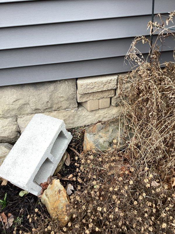 Responded to emergency water leak service call after water company shut off supply due to suspected leak on customer's property. Conducted thorough inspection of exterior foundation and surrounding area, examining the junction between vinyl siding and stone foundation where moisture indicators were present. No active leak was visually identified during this initial assessment; further investigation required.