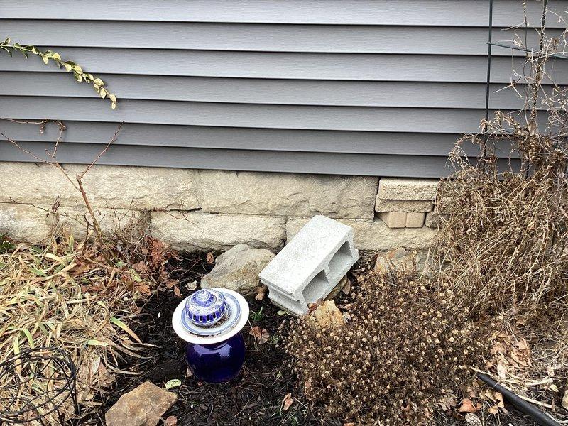 Responded to emergency water leak service call after water company shut off supply due to suspected leak on customer's property. Conducted thorough inspection of exterior foundation and surrounding area, examining the junction between vinyl siding and stone foundation where moisture indicators were present. No active leak was visually identified during this initial assessment; further investigation required.