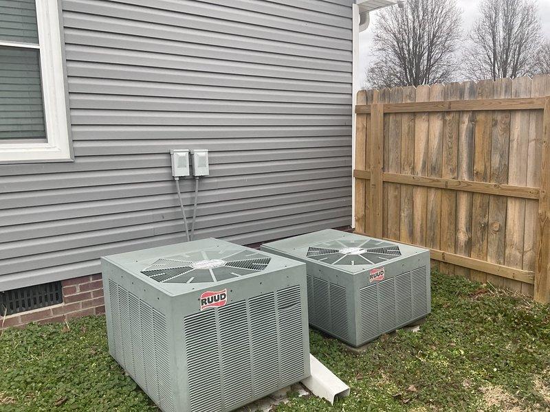 Performed full system assessment of 2004 HVAC equipment showing significant deterioration. Identified rusted burners caused by leak at inducer-to-exhaust tubing joint and documented chronic AC issues reported over past decade. Provided comprehensive replacement estimate for dual Ruud systems, noting customer is undecided on upgrade timeline. Visual inspection confirmed exterior units showing age-related wear and proper installation location adjacent to home with appropriate electrical connections.