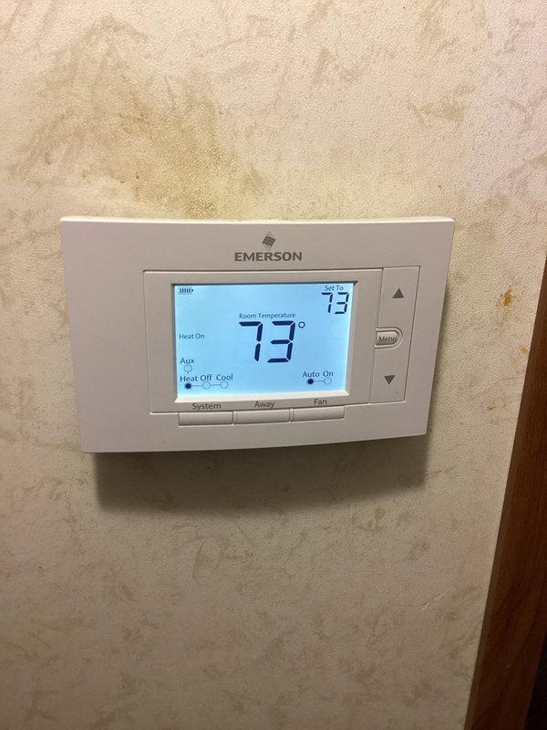 Performed monthly basic heating maintenance on Goodman CCHP unit. Inspected outdoor condenser unit and verified proper operation with thermostat set at 73°F in heat mode. System functioning correctly with "Heat On" status confirmed at the Emerson digital thermostat.