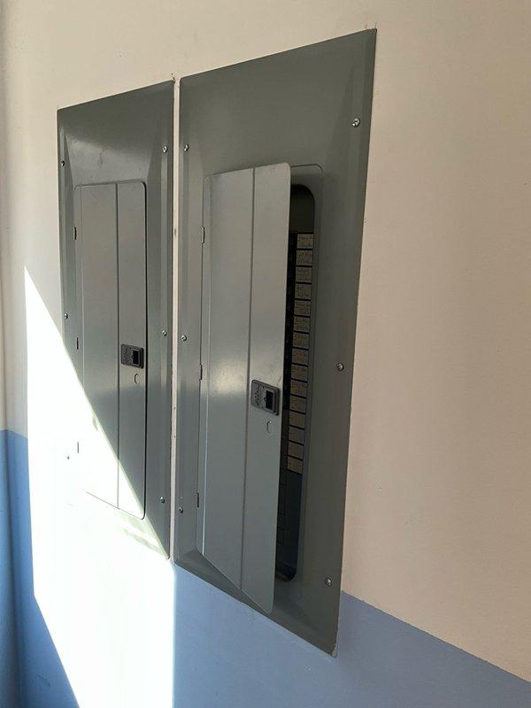 Performed on-site evaluation for potential installation of secondary AC unit in bay area, focusing on a heat pump system with gas backup. Existing heating unit was previously disabled due to compromised heat exchanger. Documented electrical infrastructure, including main breaker panel and adjacent electrical panel, to assess power capacity for proposed HVAC installation.