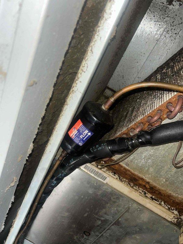 Diagnosed Goodman AC unit that was starting briefly then blowing hot air due to a refrigerant leak at the filter drier. Observed significant oxidation on copper lines and corrosion around system components. Replaced filter drier, performed leak repair, and recharged system to restore proper cooling operation.