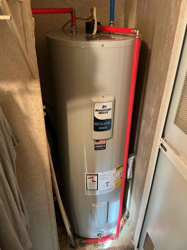 Successfully installed a Bradford White electric water heater in utility closet with proper PEX piping connections. Unit was properly secured and all supply lines were tested for leaks. Installation included connection of hot and cold water lines with appropriate valves and fittings.