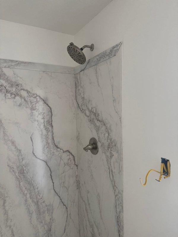 Completed final plumbing connections for new construction project including installation of kitchen sink drain assembly, dishwasher supply line, and shower fixture set with rainfall shower head. Inspected and verified proper operation of sewer pump per owner's request, and completed all required fixture connections for marble-patterned shower surround installation.