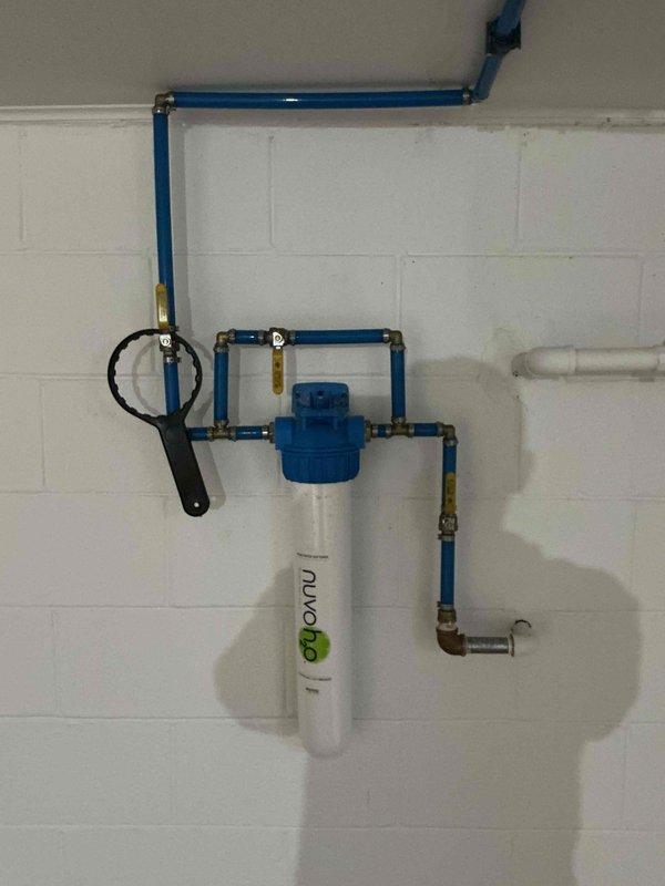 Performed prepaid plumbing inspection of customer's water treatment system, which included a nuvo H2O filter unit connected to blue PVC pipes with brass fittings in a bypass configuration. Also inspected ceiling access areas where plumbing penetrations were visible and examined PVC drain pipe with cleanout cap; all components appeared to be in proper working condition with no visible leaks or damage.