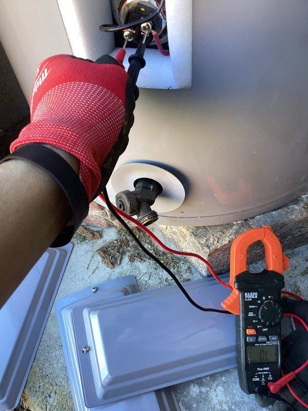 Diagnosed and performed electrical testing on non-operational commercial tanked water heater at rear of building. Used Klein Tools clamp meter to check voltage and electrical components, accessing internal wiring through service panel. Testing confirmed electrical failure as source of water heater malfunction.