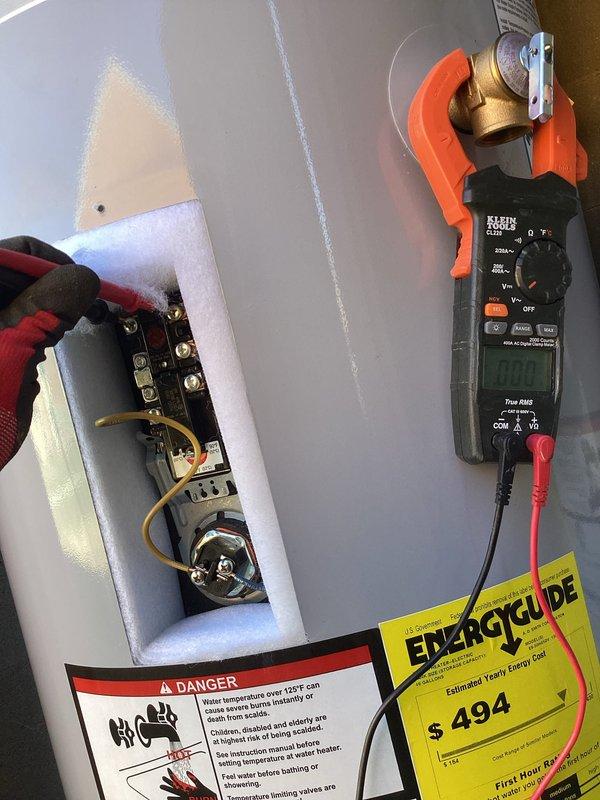 Diagnosed and performed electrical testing on non-operational commercial tanked water heater at rear of building. Used Klein Tools clamp meter to check voltage and electrical components, accessing internal wiring through service panel. Testing confirmed electrical failure as source of water heater malfunction.