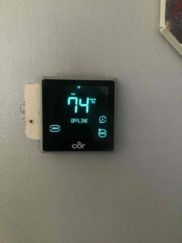 Performed Basic Plus maintenance on CCHP heating system. Inspected thermostat displaying "OFFLINE" status with heat mode active at 74°F. Evaluated outdoor unit condition, confirmed proper installation on gravel bed with intact connections to building.