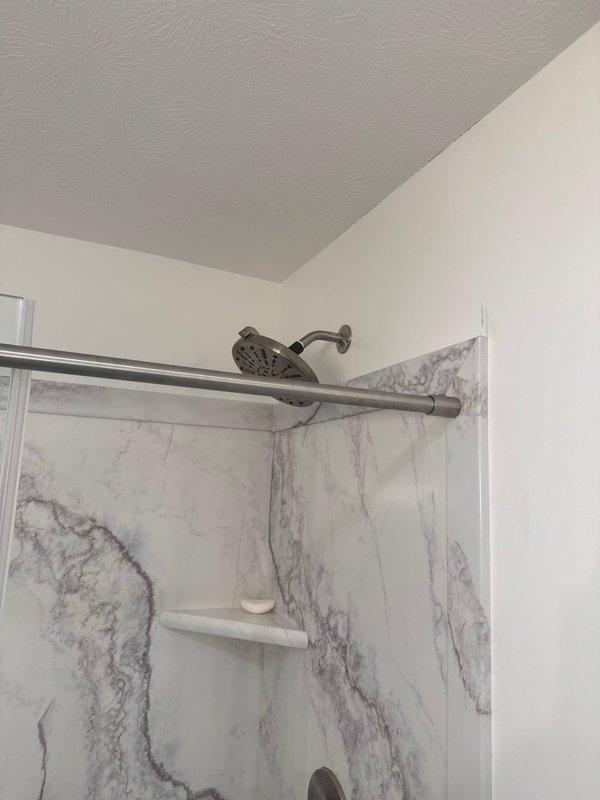 Secured two loose shower heads in wall mounts and restored hot water flow to guest bathroom shower by clearing obstructions in the hot water supply line and adjusting the mixing valve.